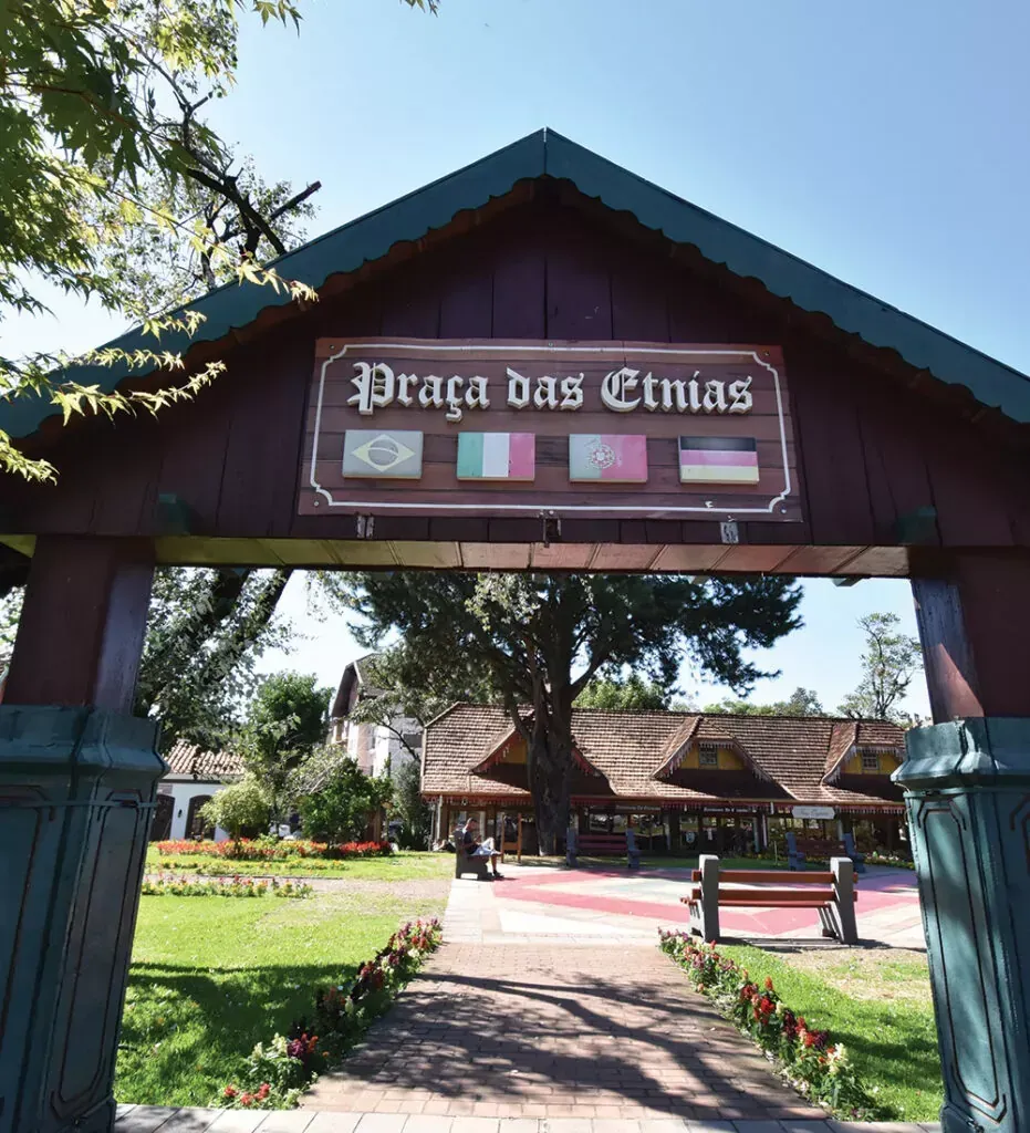 Wooden entrance arch lendo “Praça das Etnias” over a path in a sunny park.