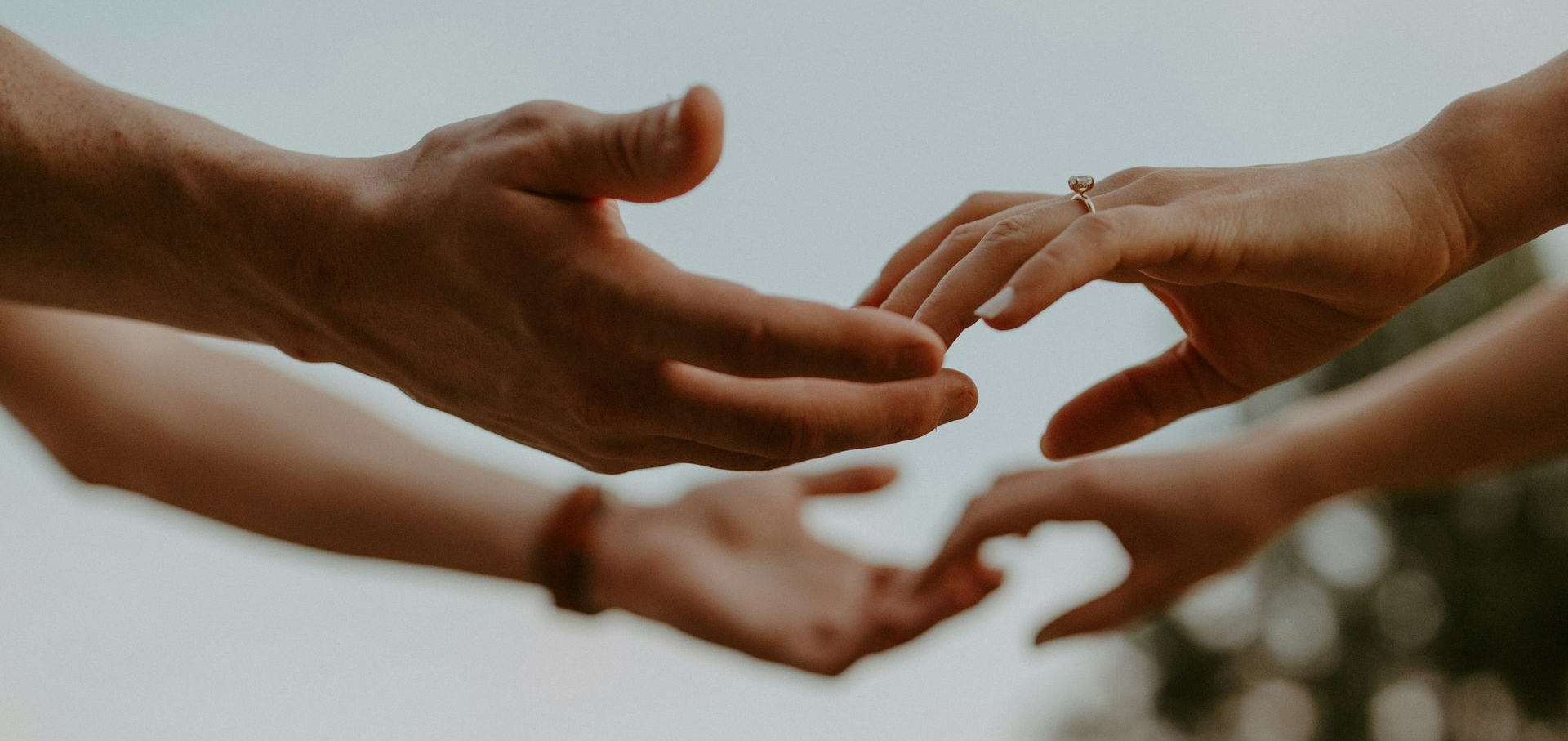 Two hands, one with a ring, clasped together in the warm glow of sunlight.