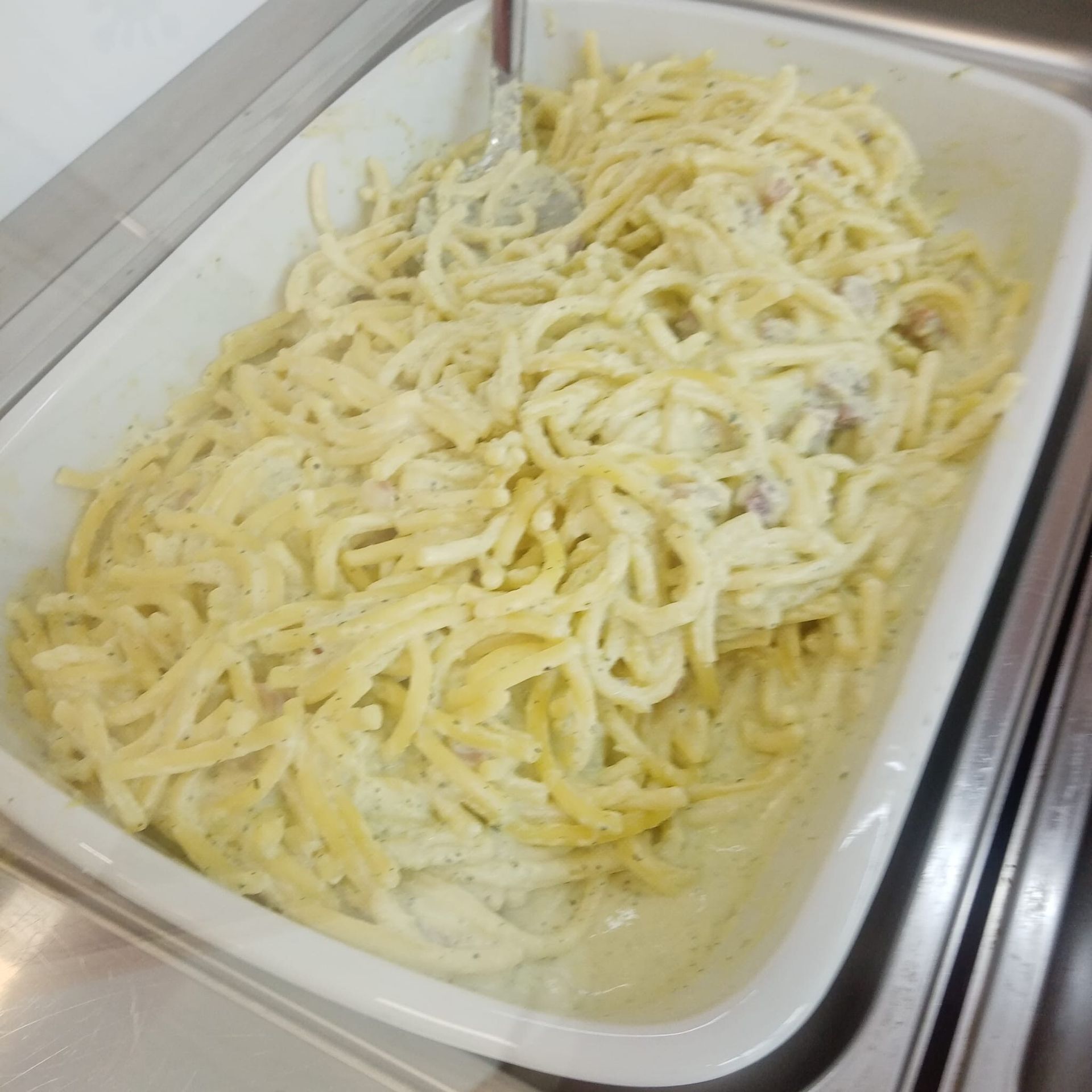 Pasta alla carbonara in un piatto da portata bianco.