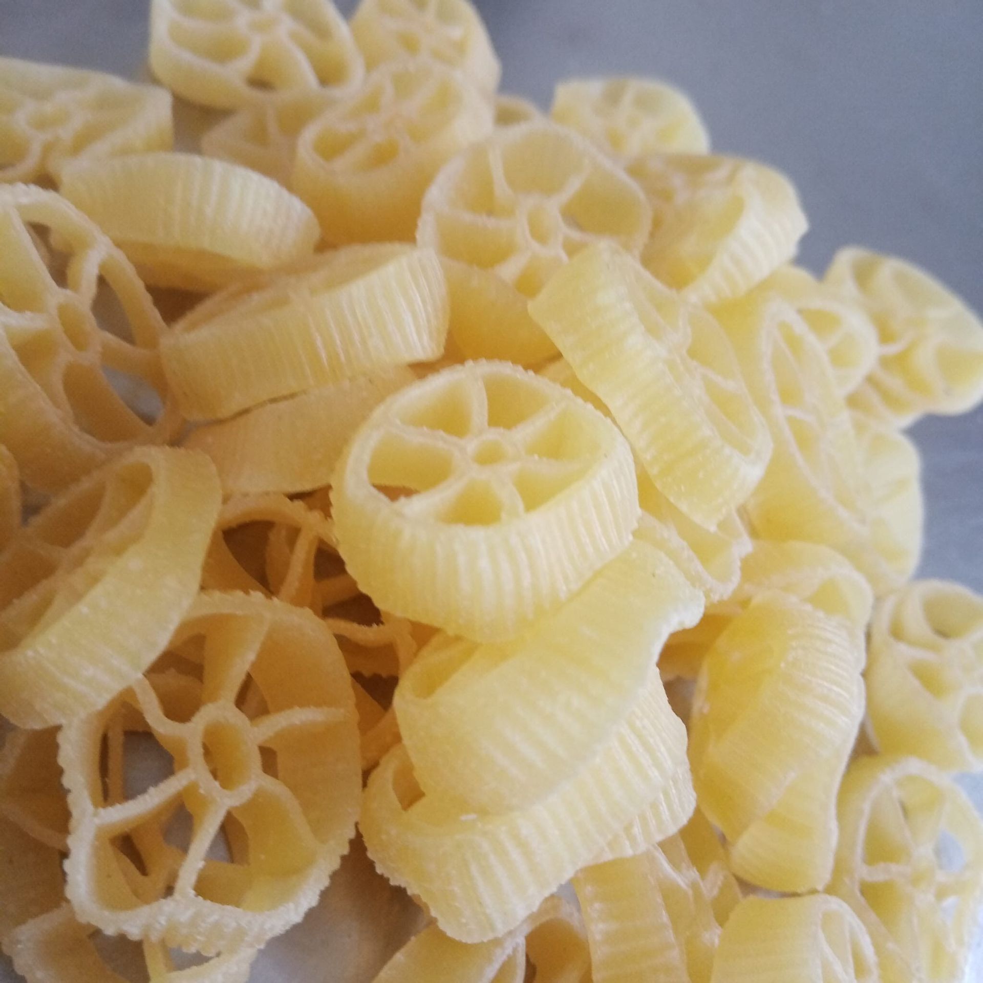 Mucchio di pasta rotelle cruda, di colore giallo-beige.