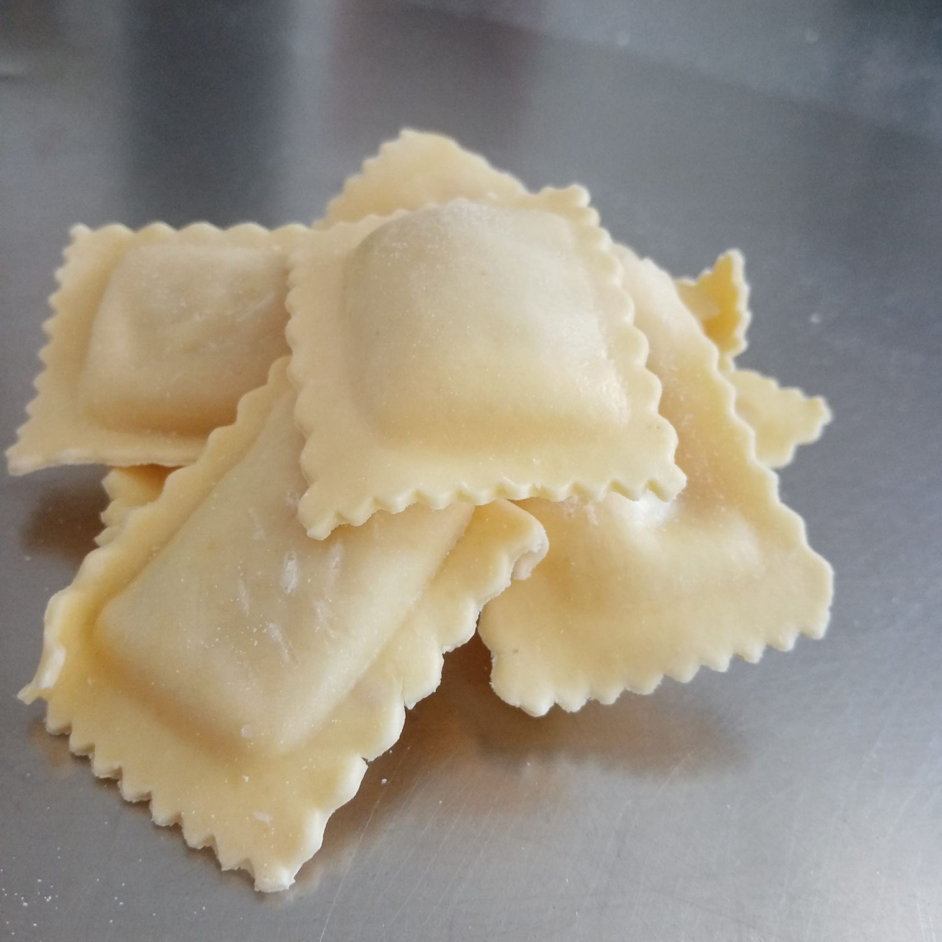 Mucchio di ravioli quadrati crudi con i bordi arricciati.