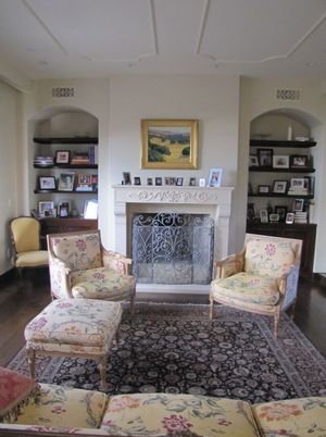 Living room with floral armchairs, fireplace, and built-in shelves in neutral tones