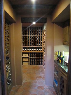Tiled wine cellar with bottle racks lining the walls and a central display shelf at the back
