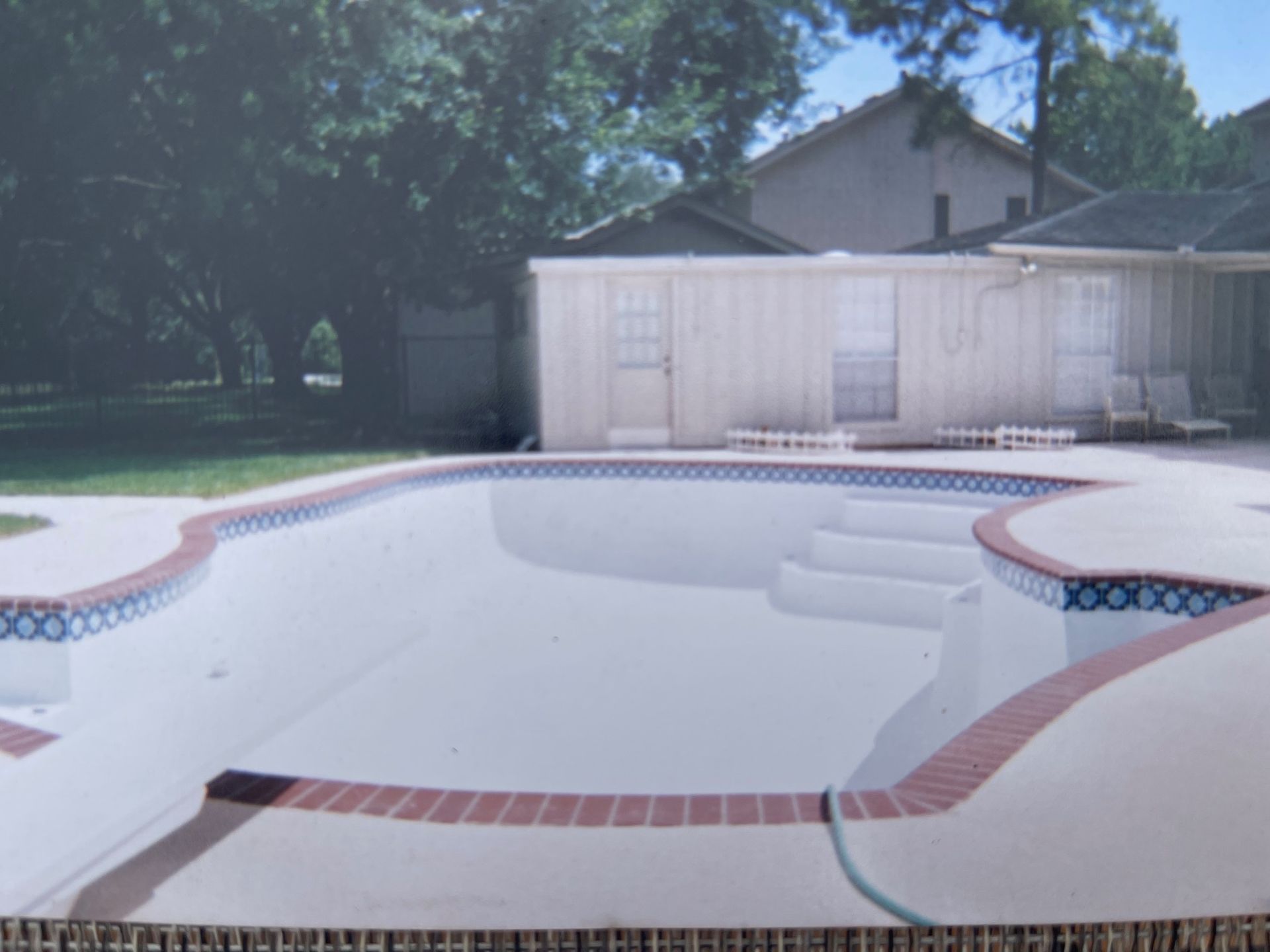 A picture of a swimming pool with a house in the background
