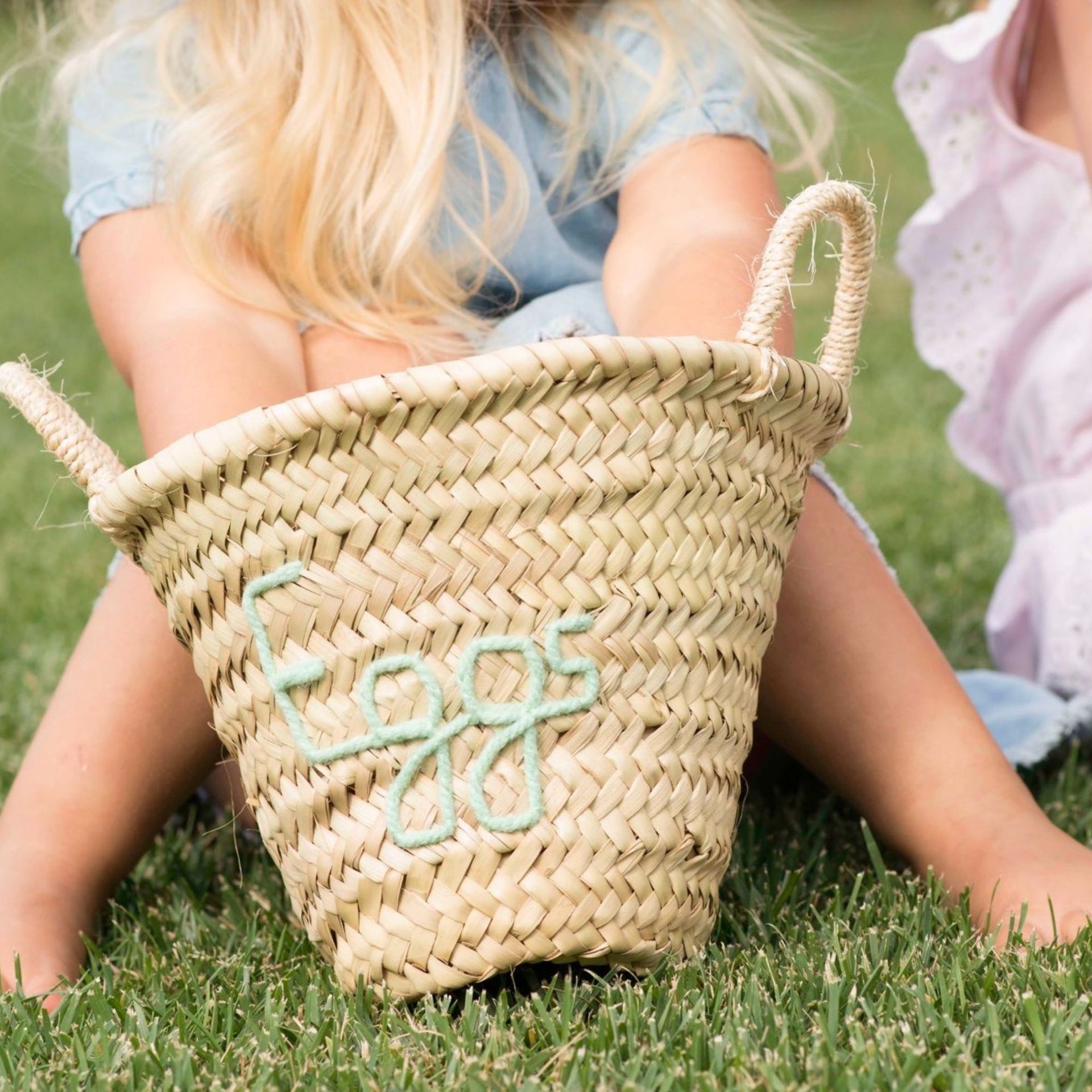 Petite fille portant un panier de Pâques brodé