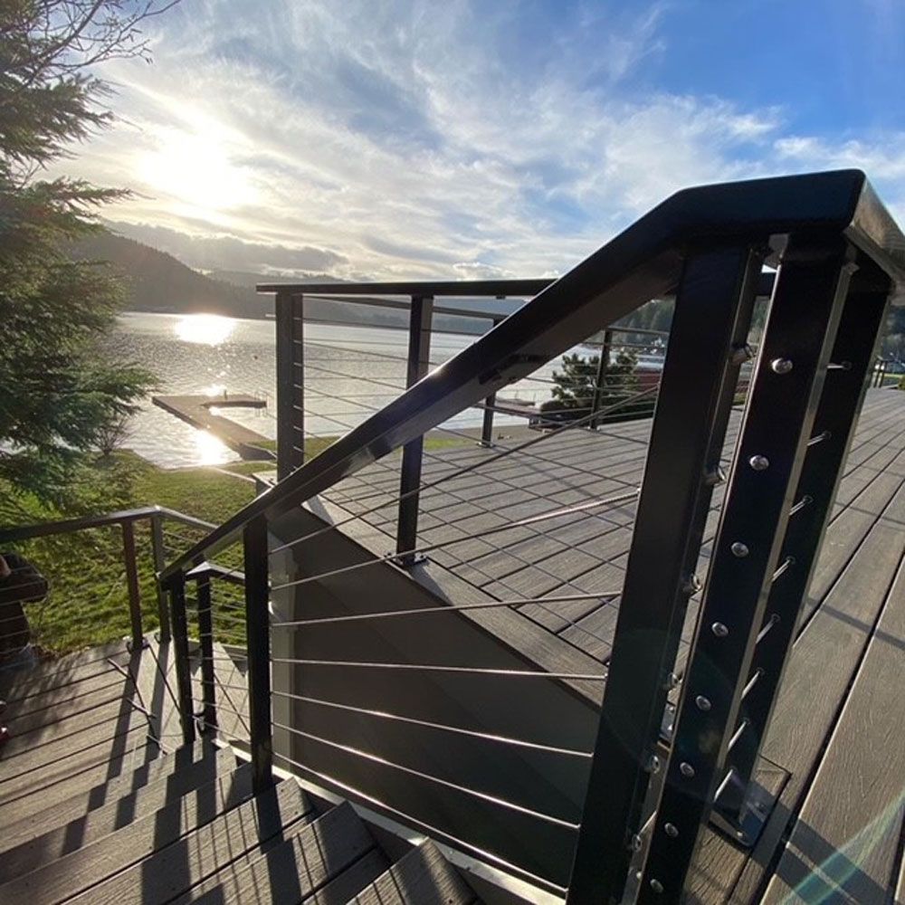 Deck stair railing with custom welded steel cable railing overlooking waterfront
