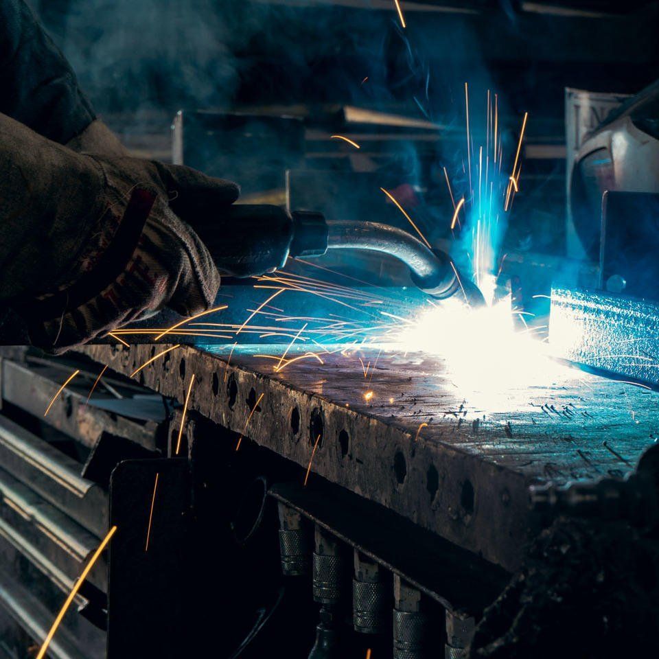 Close-up of welding torch creating sparks on steel work surface