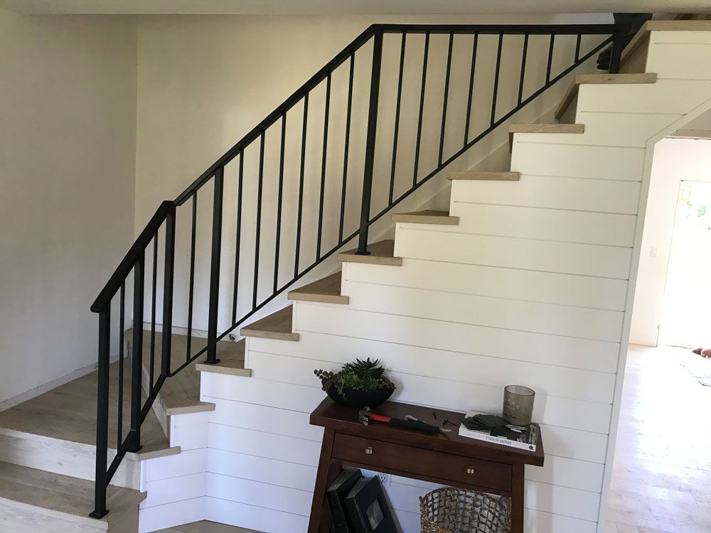 Interior staircase with custom welded steel railing system and vertical balusters