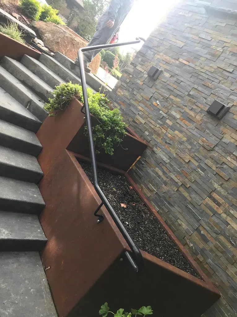 Concrete stairway with integrated metal planter and custom welded steel handrail