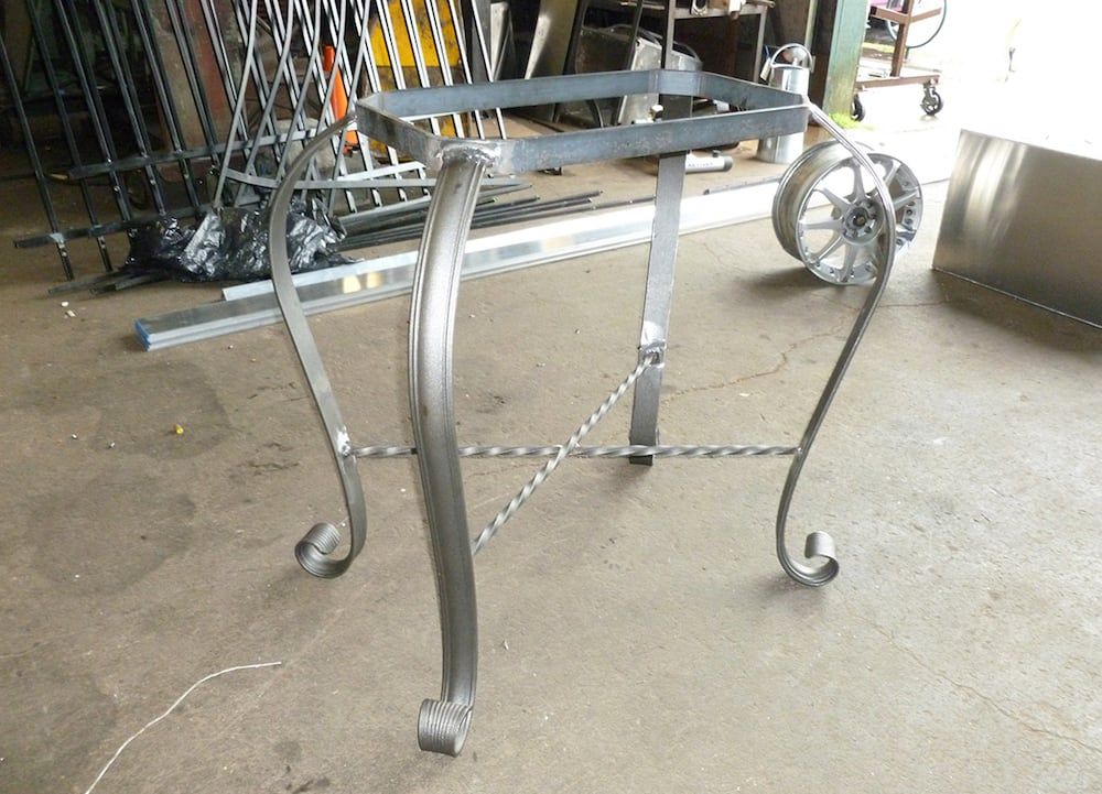 Custom fabricated metal table base with welded steel curved legs