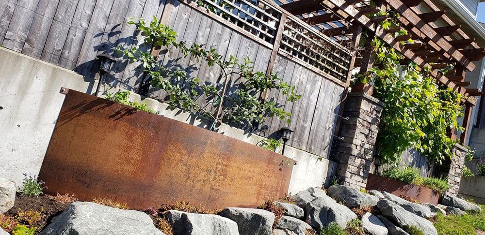 Custom fabricated steel retaining wall with integrated planter feature