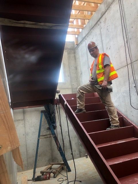 Worker guiding structural steel stair section into place during installation