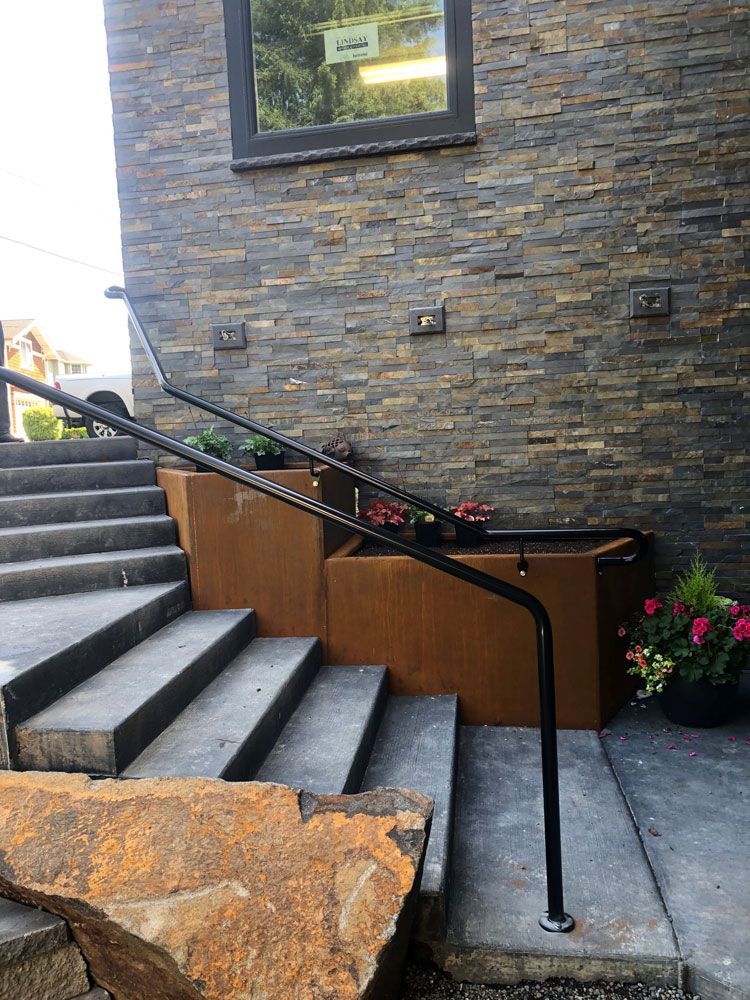 Residential concrete stairway with custom welded steel handrail and integrated metal planter