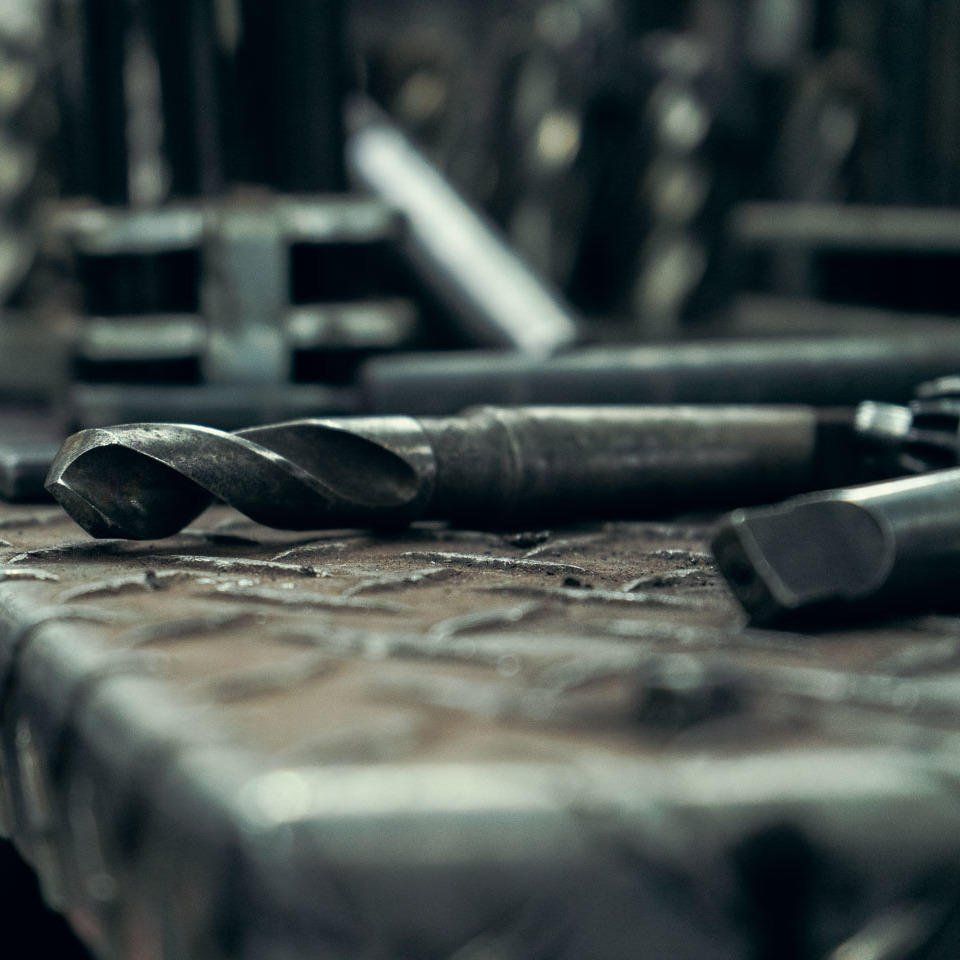 Metal drill bits and tooling on workbench in fabrication shop