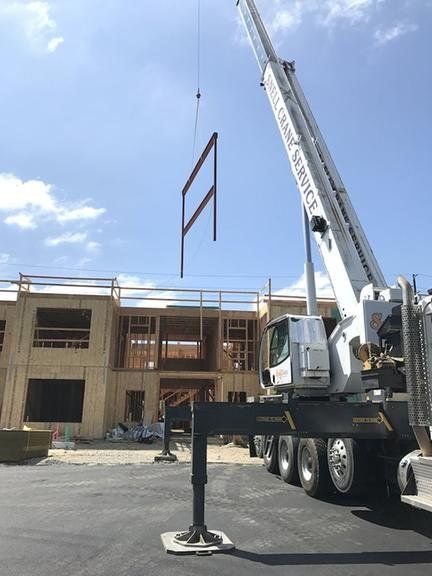 Crane lifting structural steel frame into place at construction site