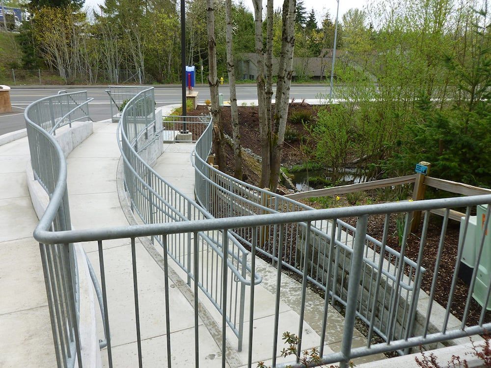 Curved ADA-compliant metal walkway railing in landscaped area