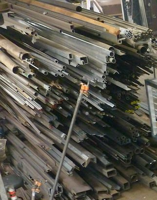 Stacked aluminum and steel bar stock stored vertically in shop