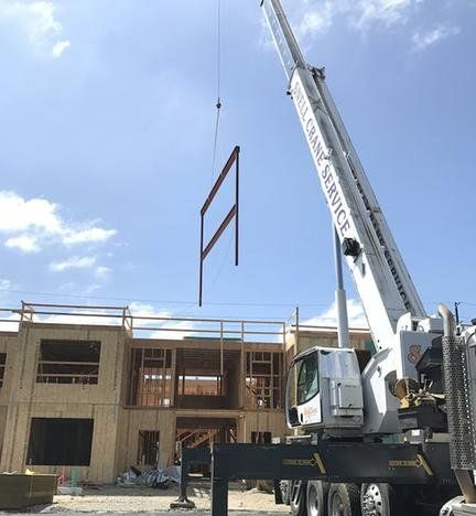 Structural steel installation with crane lifting steel framing into place on construction site