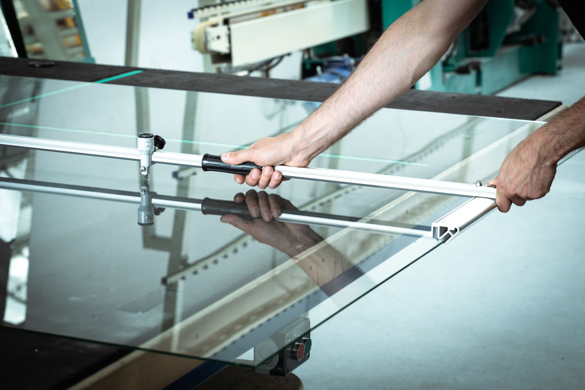 A man is cutting a piece of glass with a saw.