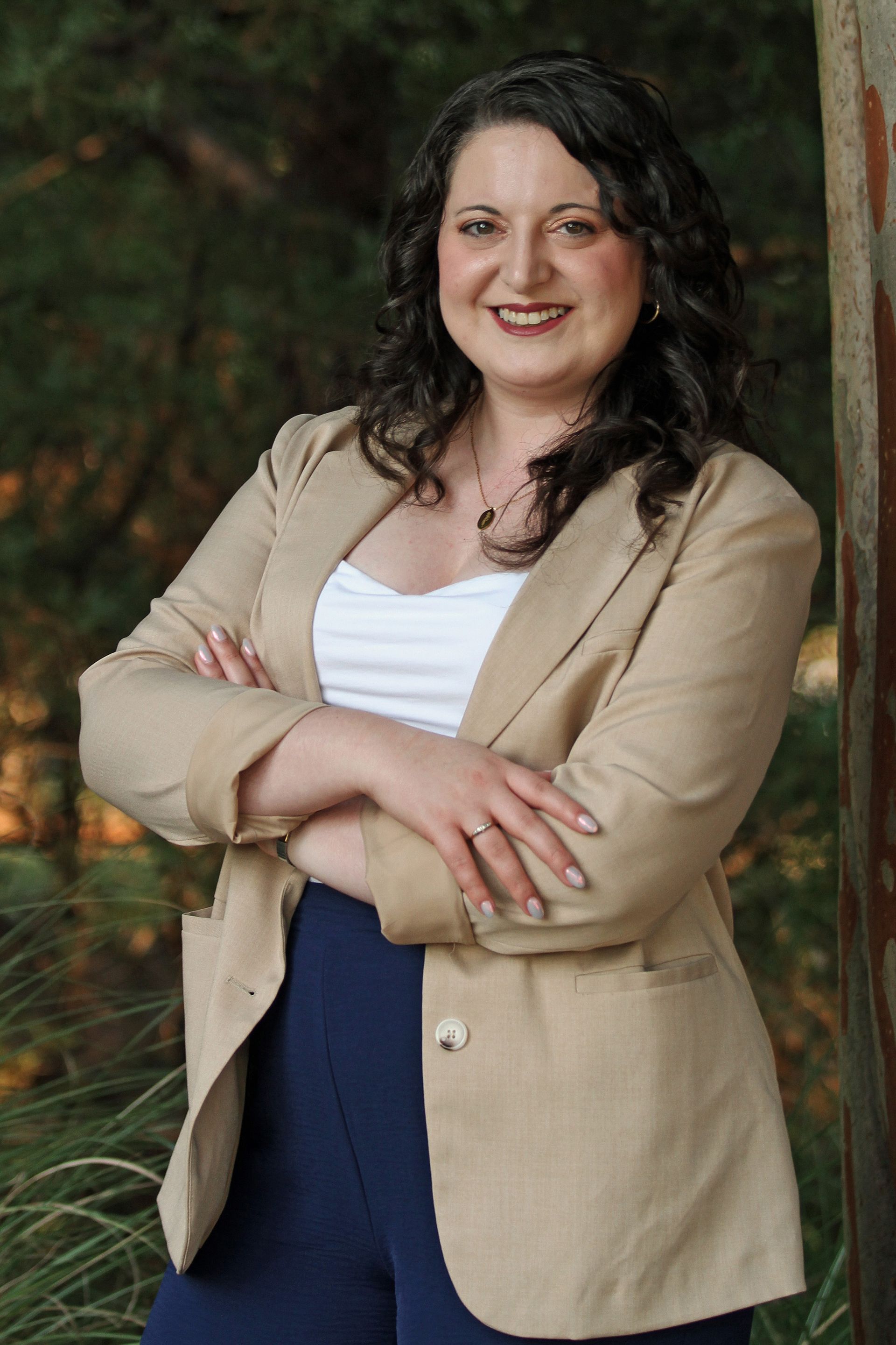 Woman in an olive green dress smiling against a light gray background