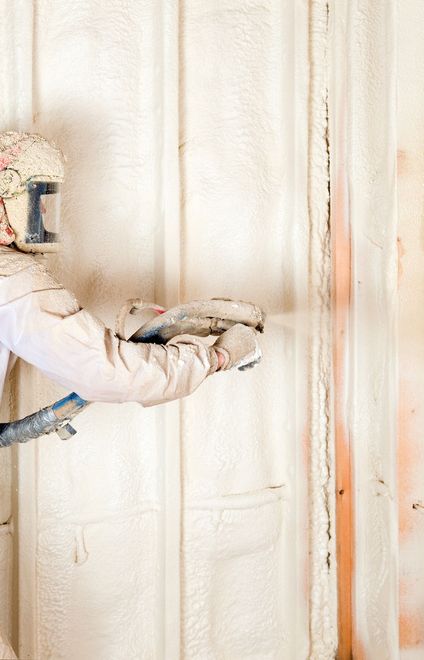 A man is spraying foam insulation on a wall.