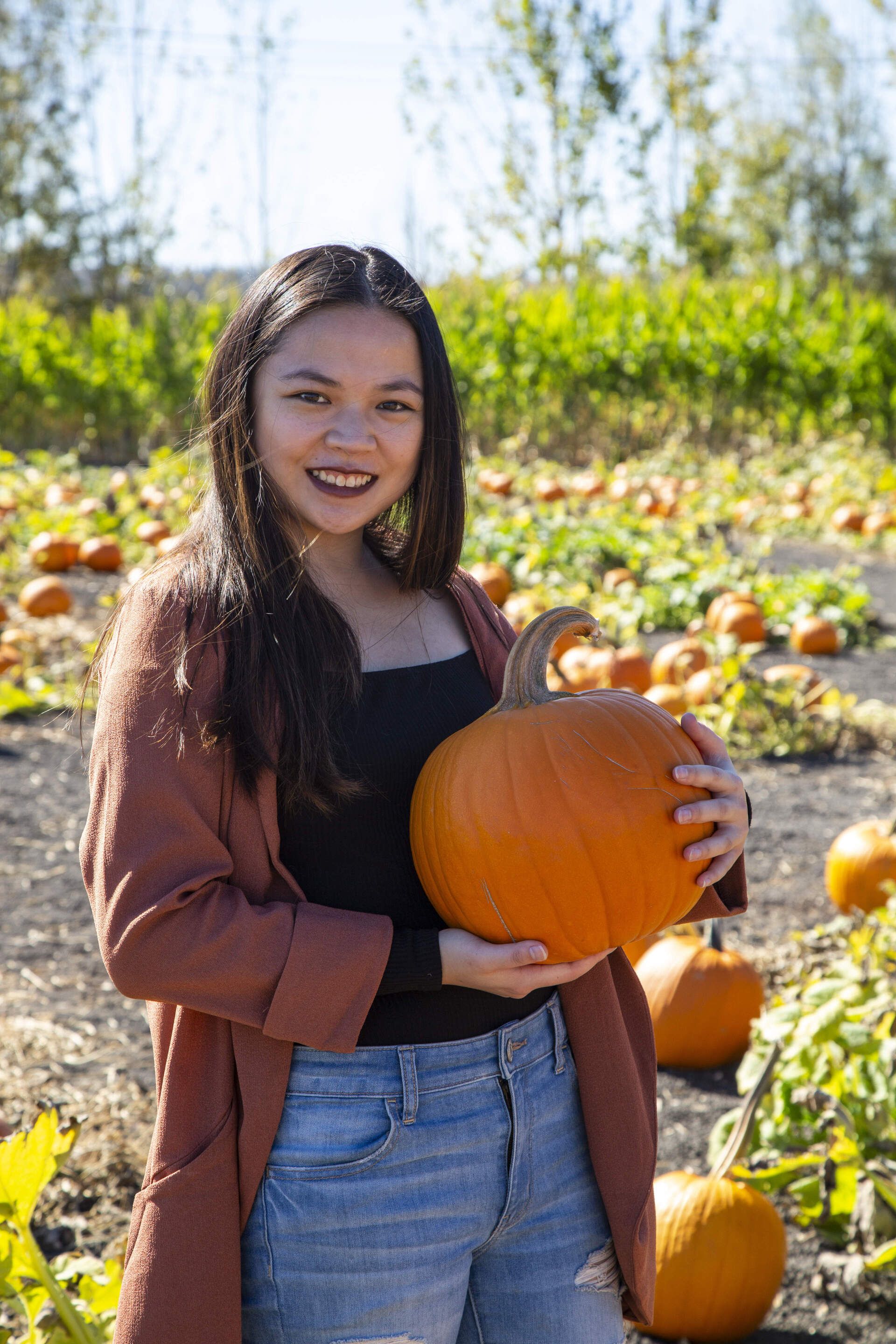 girl holding a pumpkin, smiling