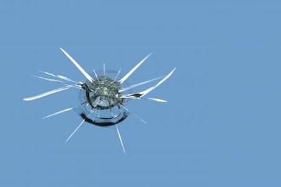Cracked blue glass with a central shattered impact and white fissures spreading outward