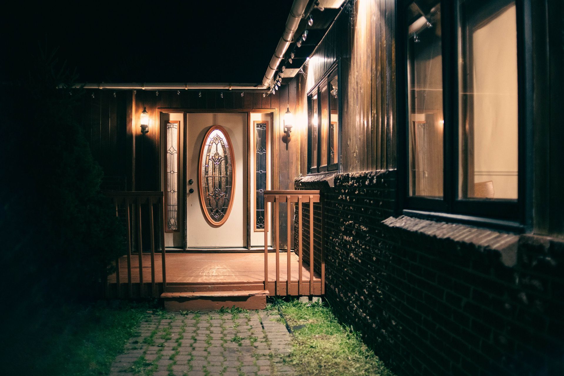 A warmly lit house entrance with decorative glass doors and glowing lantern lights at night