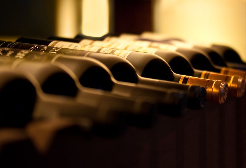 Bottles of Wine on a Rack Necks Lined Up, Labels Visible, Soft Lighting — BYO Cellars in Forster, NSW