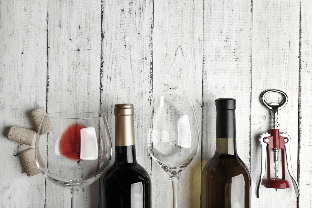 Wine Bottles, Glasses, Corks, and a Corkscrew on a White Wooden Surface — BYO Cellars in Wyong, NSW