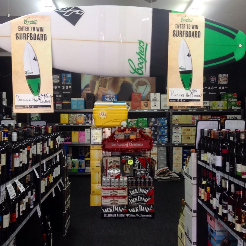 Liquor Store Interior With Shelves of Bottles and a Surfboard Advertising a Contest — BYO Cellars in Nelson Bay, NSW