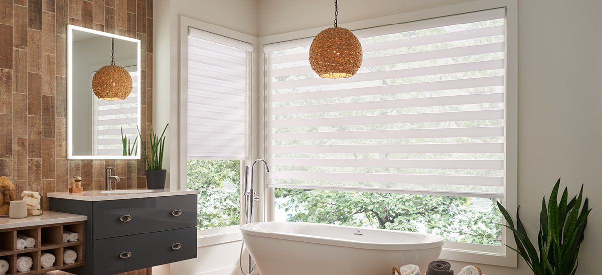 A bathroom with a tub , sink , mirror and window.