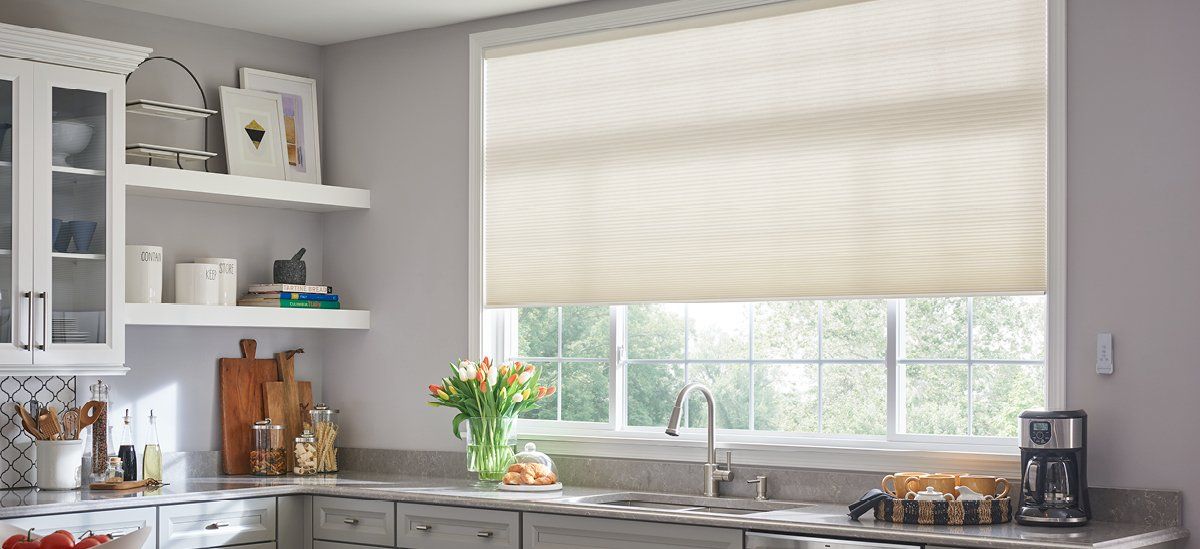 A kitchen with white cabinets , a sink , and a large window.
