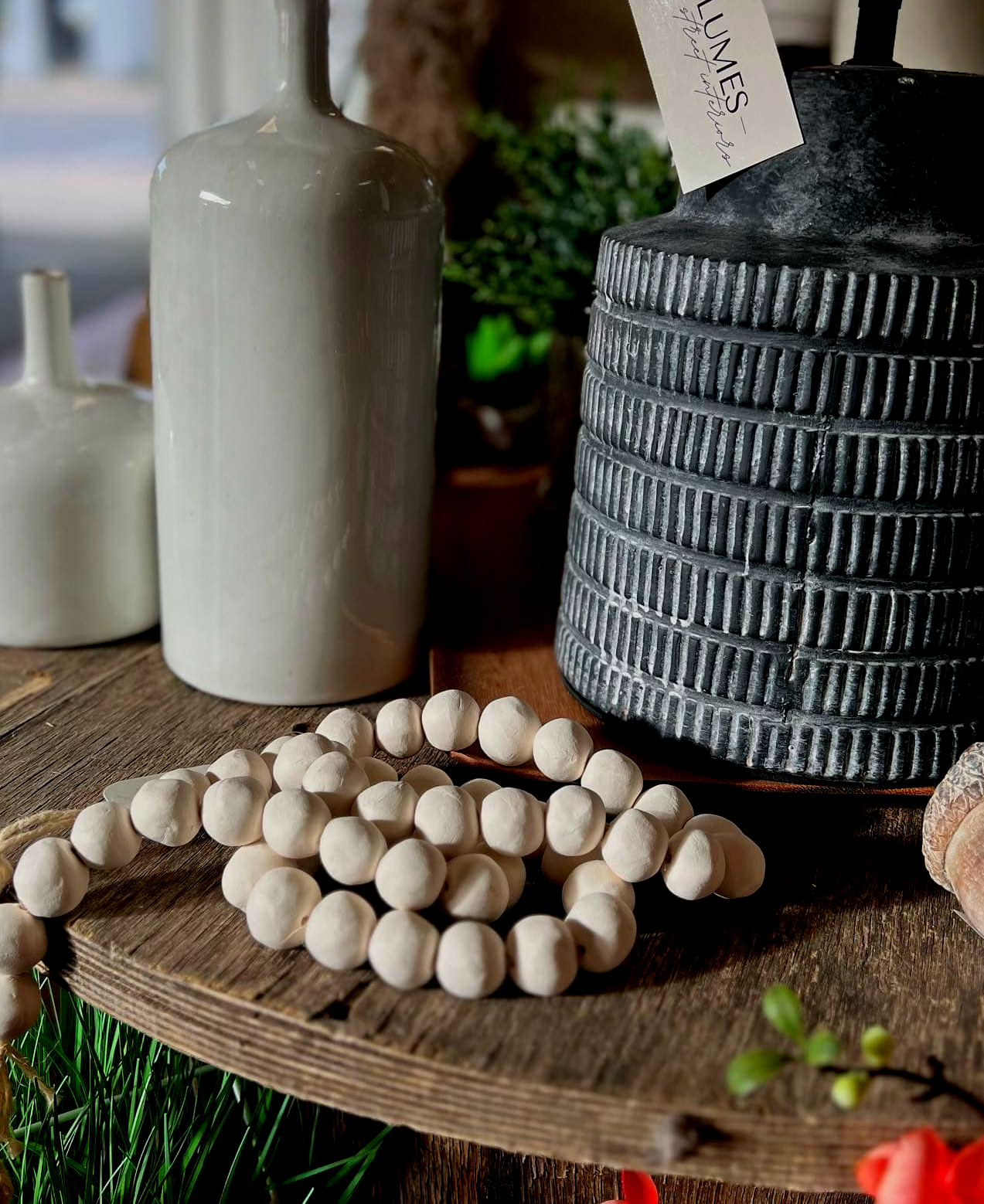 A table with a lamp , vases , and beads on it.