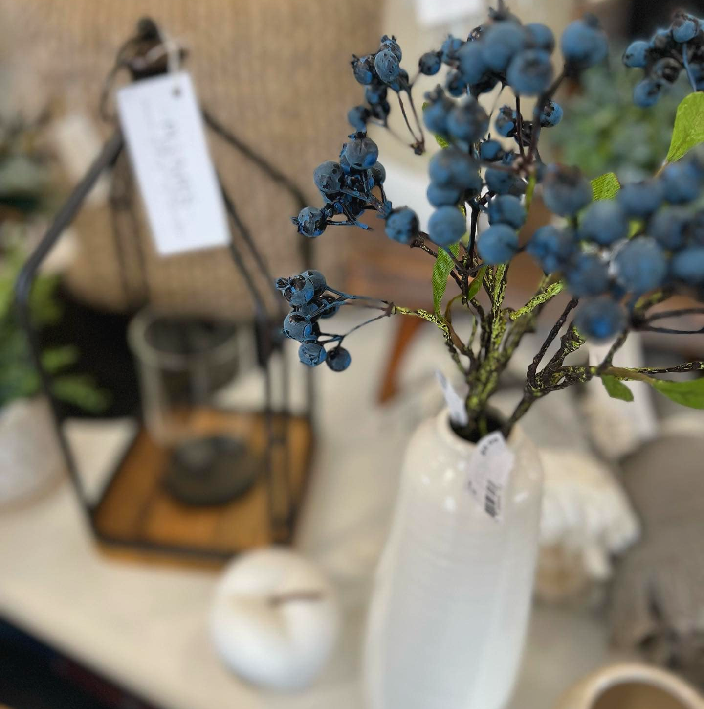 A vase filled with blue berries is sitting on a table.