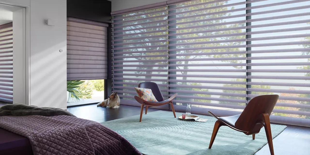 A bedroom with a bed , chair , rug and blinds.