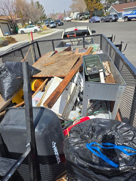 A trailer filled with construction debris, including wood and metal, sits on a street.