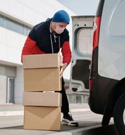 Delivery person in face mask stacking boxes next to a van.