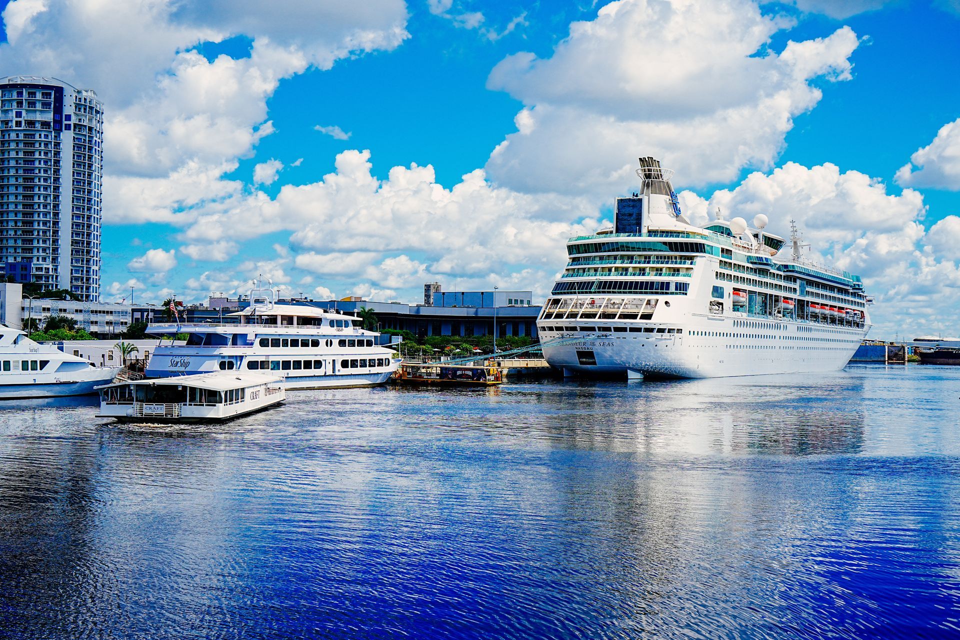 A cruise ship is docked in a harbor with boats in the water.