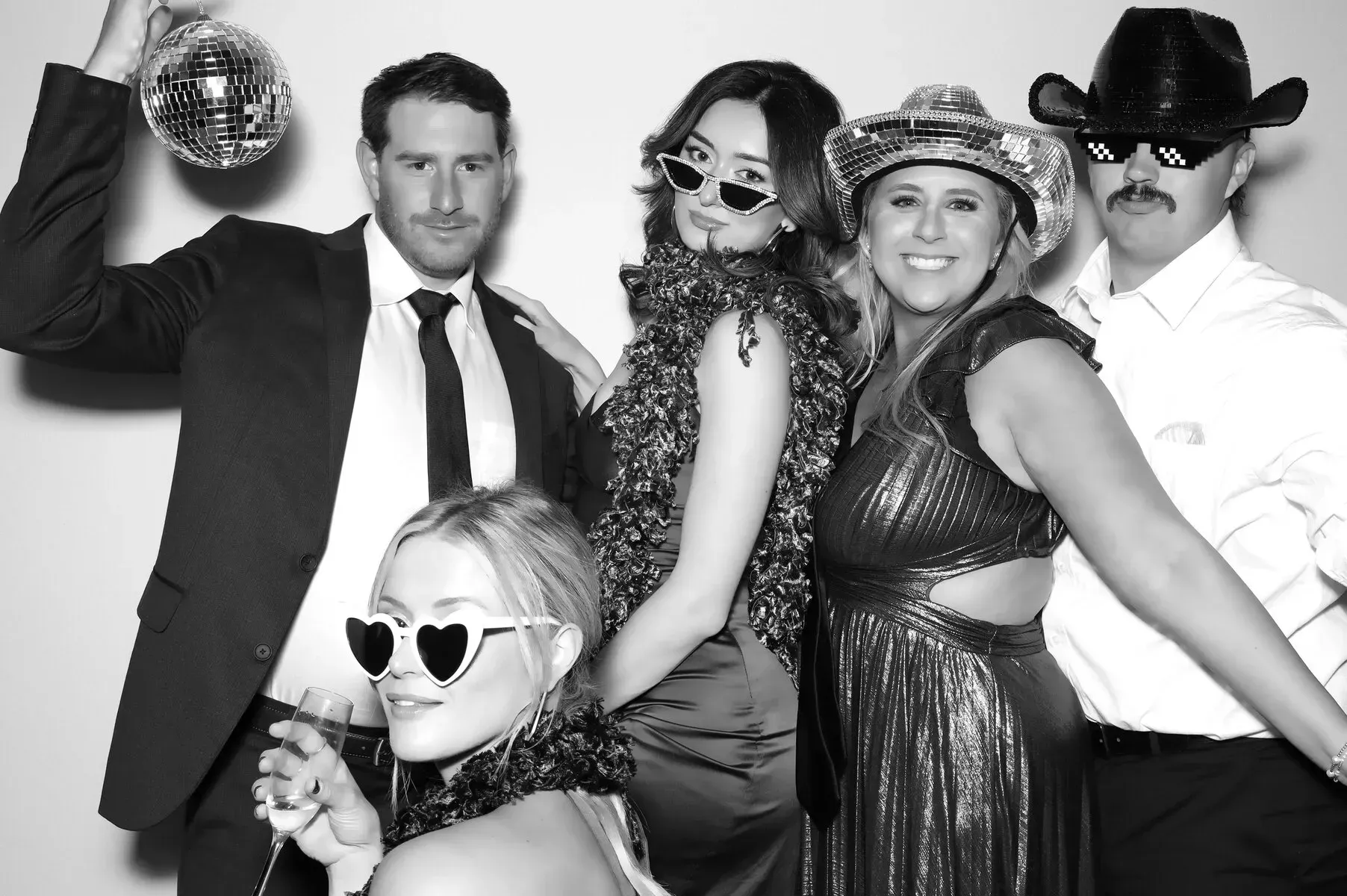 Five people posing for a photo, dressed in party attire, holding props. Black and white.