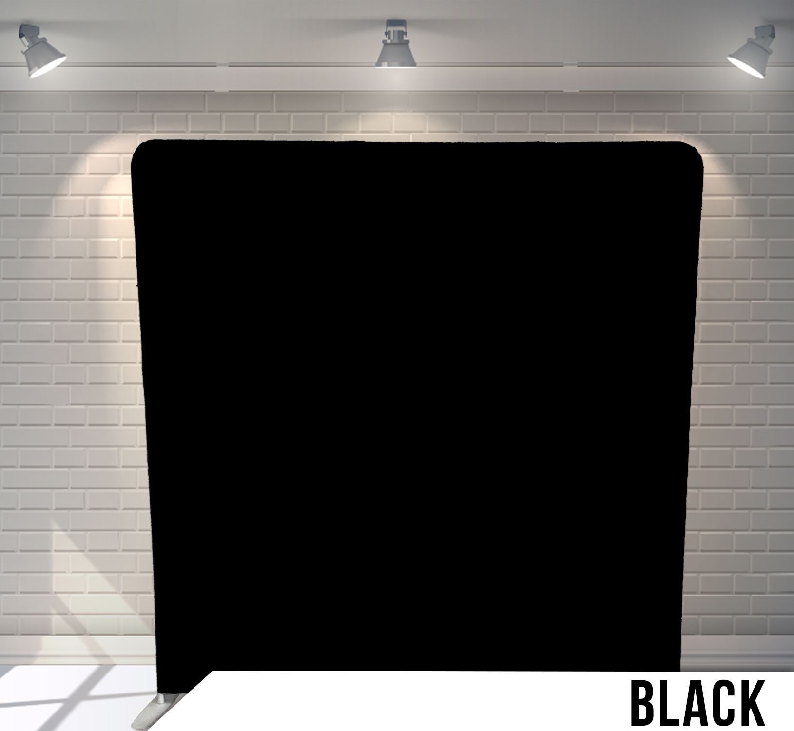 Black backdrop against a white brick wall, lit by overhead spotlights.