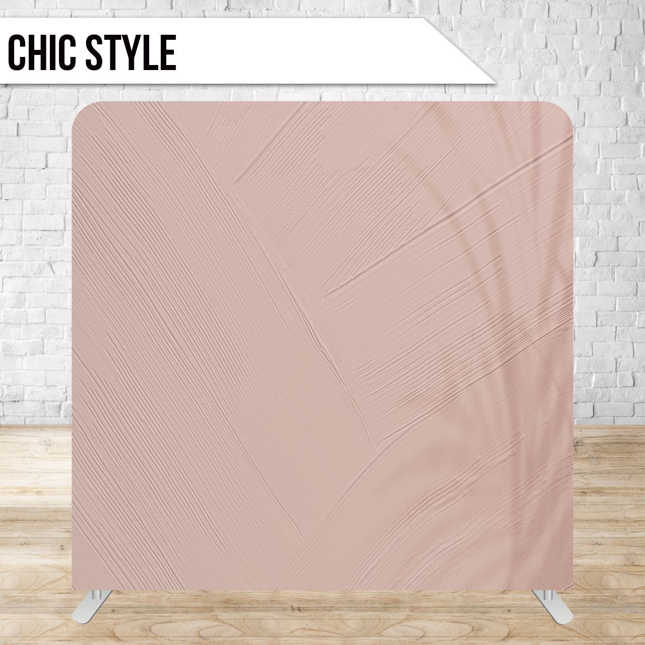 A light pink textured backdrop with subtle palm leaf shadows against a white brick wall and wood floor.