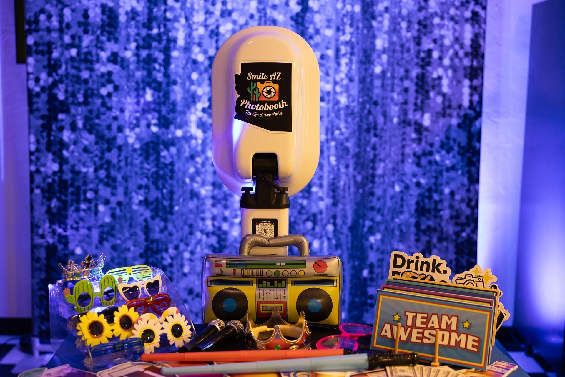 Photo booth setup with a boombox base, props, and a sequin backdrop.