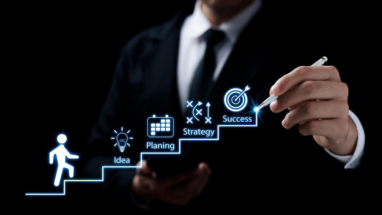 Businessman drawing a success plan with steps: idea, planning, strategy, and success.