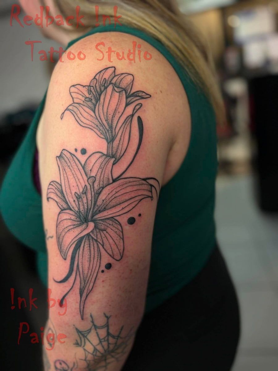 Upper Arm Tattoo of Two Outlined Lilies on a Person’s Shoulder — Redback !nk Tattoo Studio in Kawana, QLD