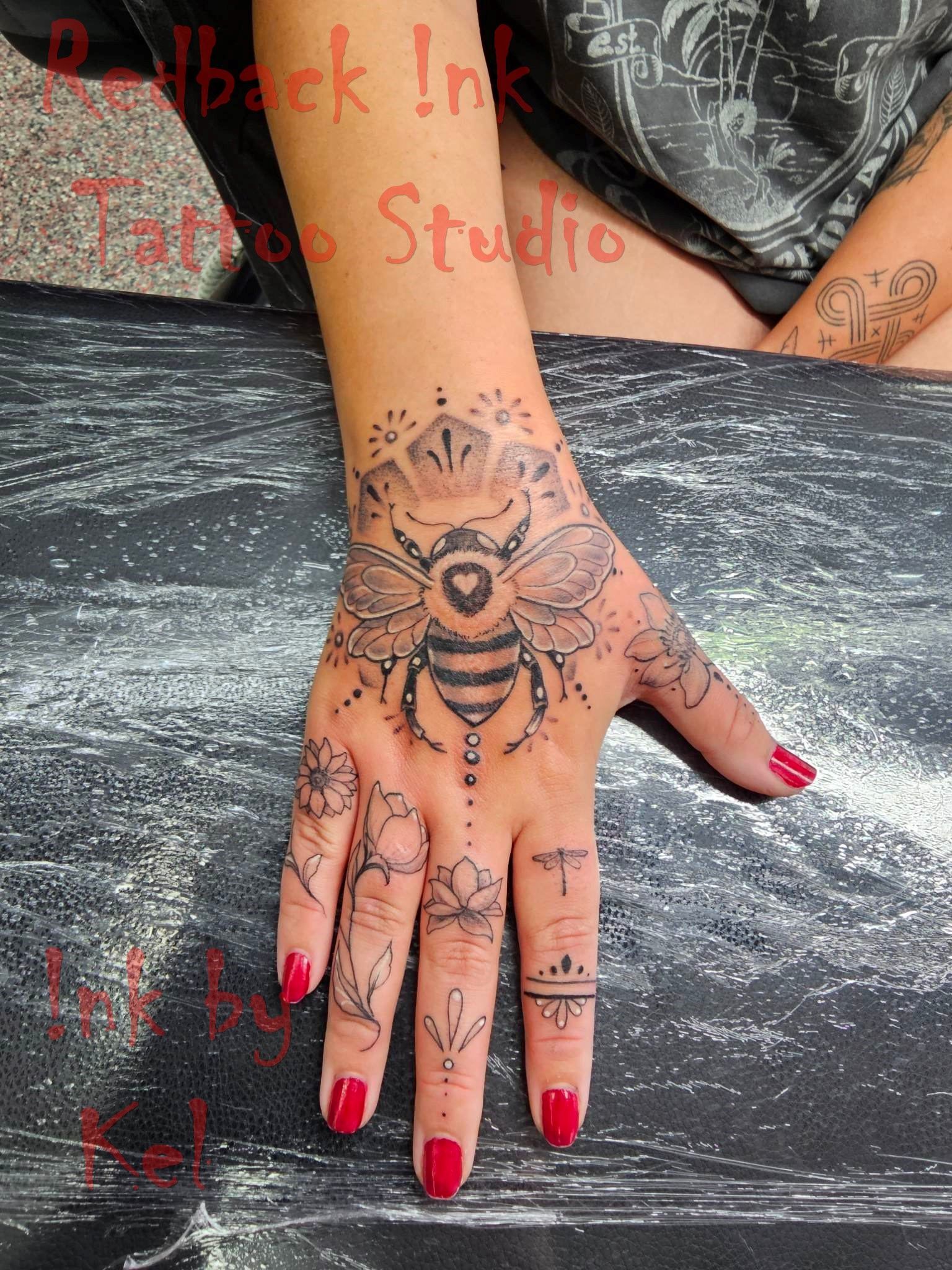 Hand Tattoo of a Bee With Floral Accents — Redback !nk Tattoo Studio in Kawana, QLD