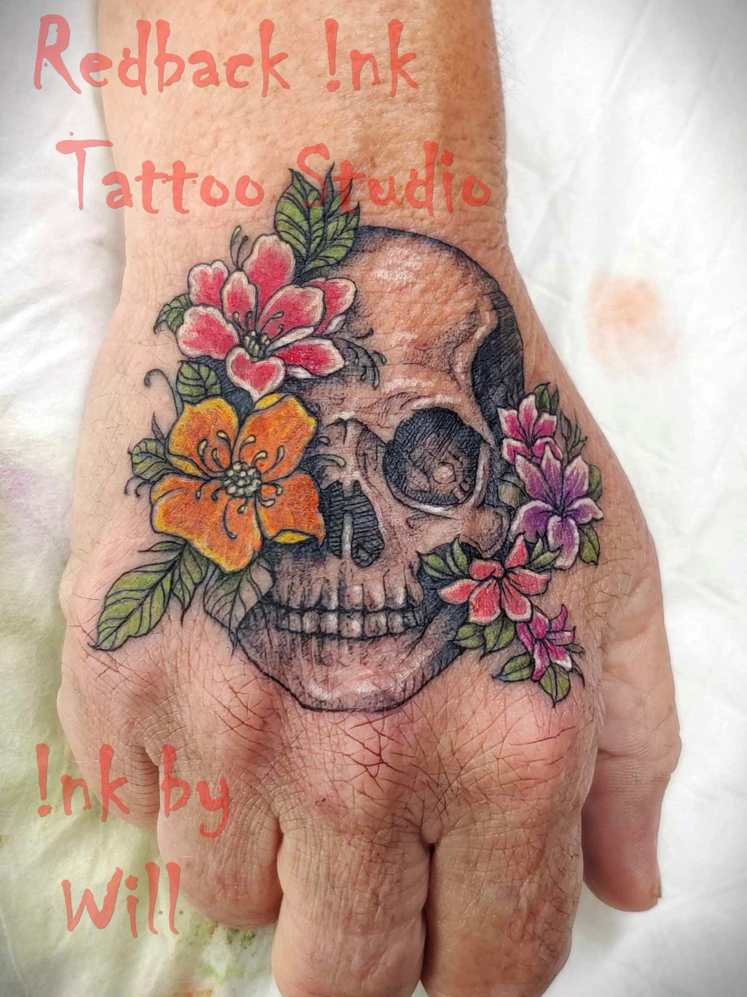 Skull Tattoo With Colourful Flowers on a Hand — Redback !nk Tattoo Studio in Kawana, QLD
