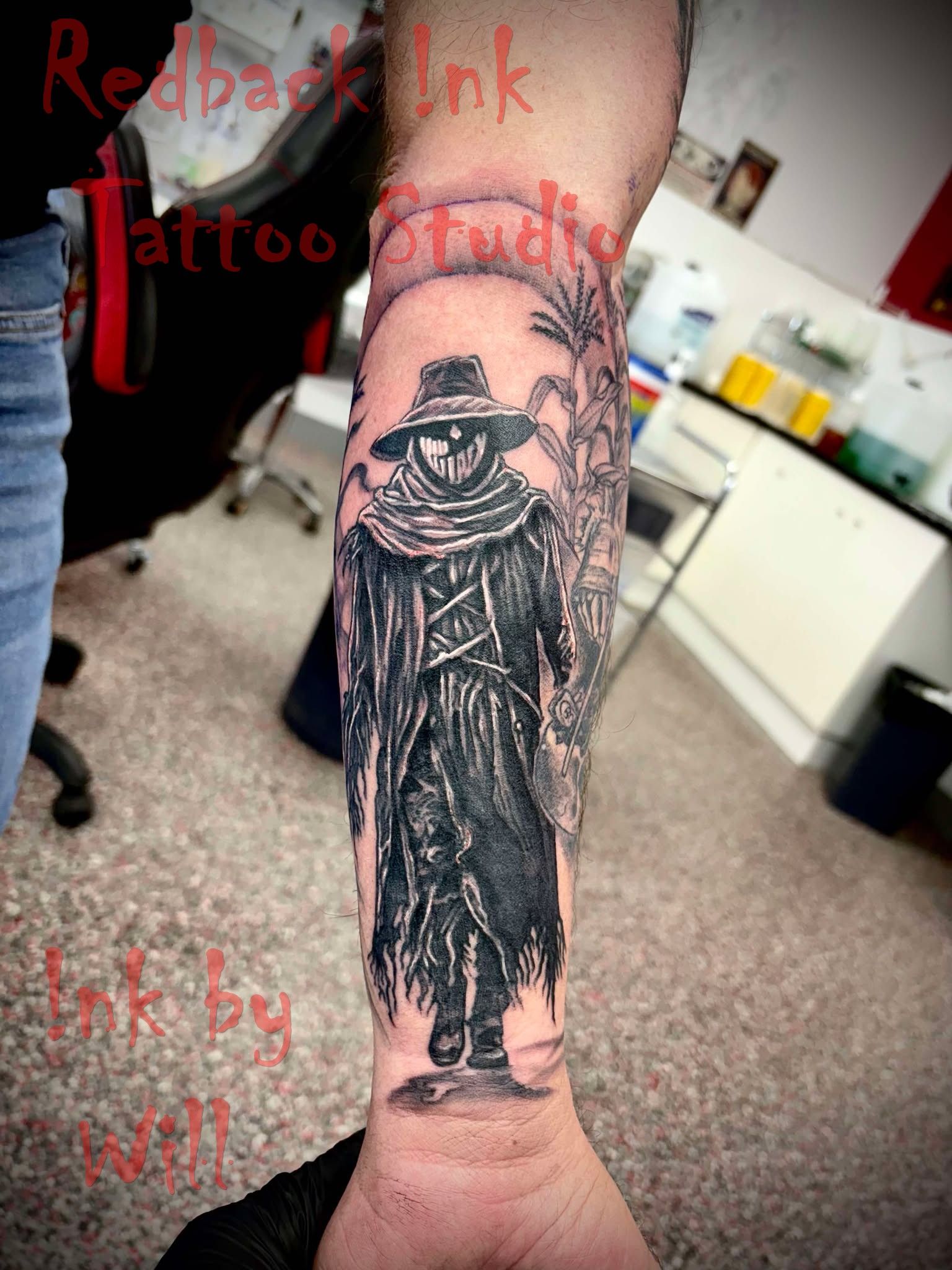 Black and Gray Forearm Tattoo of a Scarecrow Wearing a Hat and Coat — Redback !nk Tattoo Studio in Kawana, QLD