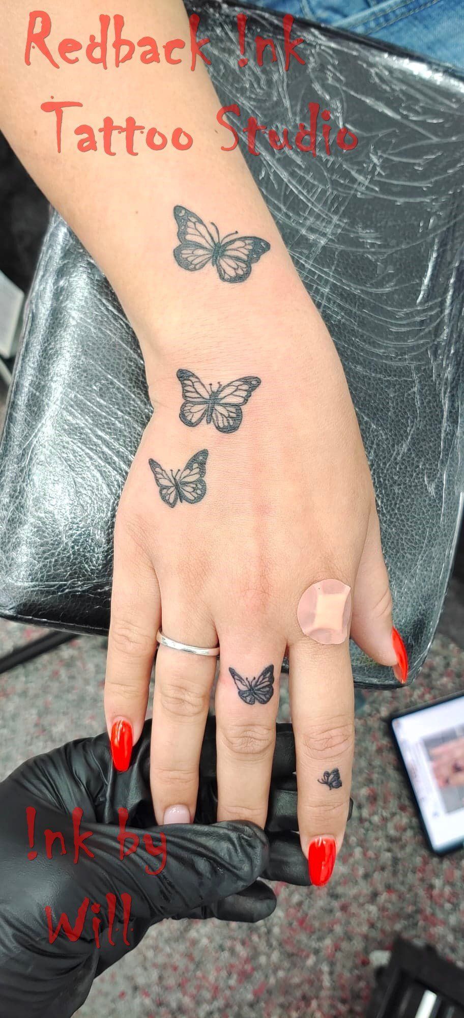 Hand With Butterfly Tattoos; a Finger Has a Bandage and Red Nails — Redback !nk Tattoo Studio in Kawana, QLD
