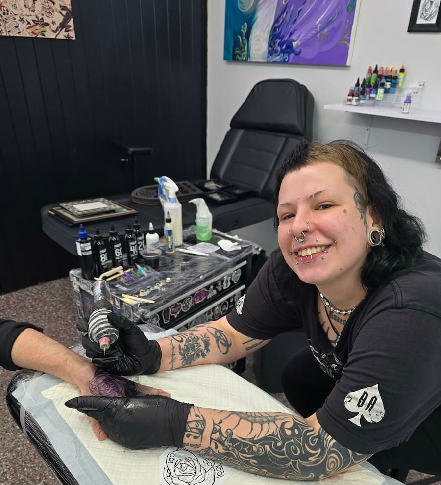 Tattoo Artist Smiling While Tattooing a Forearm at a Black Workstation in a Studio — Redback !nk Tattoo Studio in Kawana, QLD
